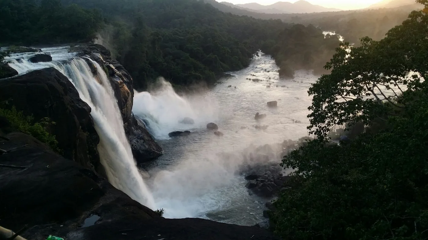 Wide view of Athirappilly Falls and the Chalakudy River at sunset