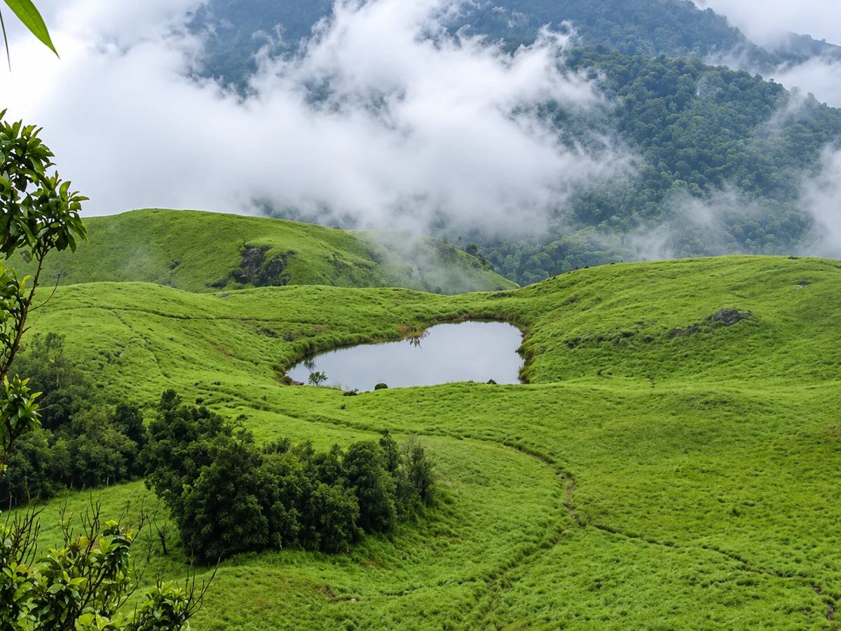 The heart-shaped lake amid misty green slopes near Chembra Peak